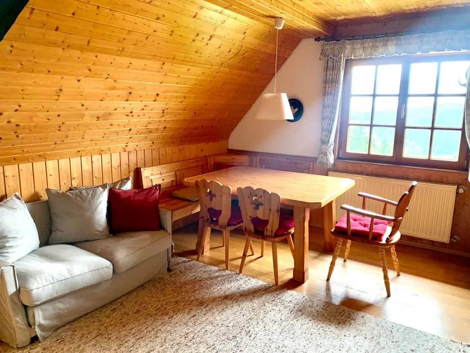 Ferienwohnung Talseite: Sitzecke mit ausziehbarer Couch und Esstisch unter der Dachschräge